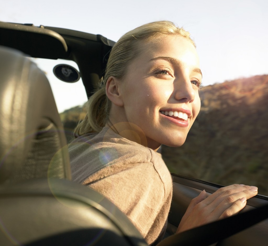 Young Woman Sits in the Front Seat of a Convertible Looking at the View --- Image by © Ocean/Corbis